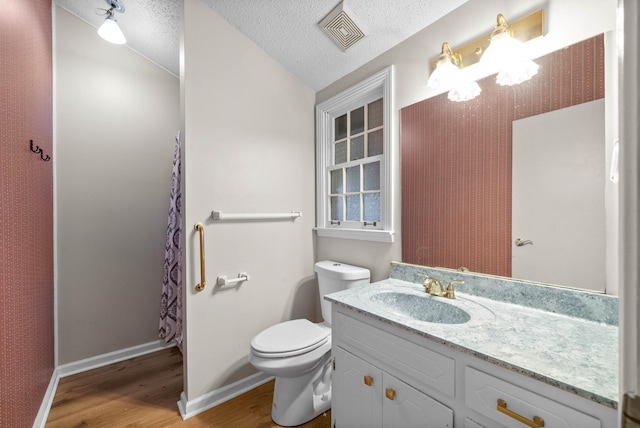 bathroom featuring vanity, hardwood / wood-style floors, a textured ceiling, and toilet