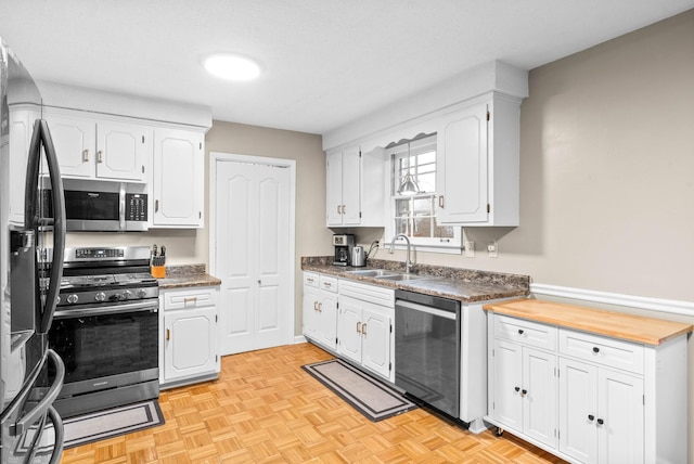 kitchen with stainless steel appliances, light parquet flooring, sink, and white cabinets