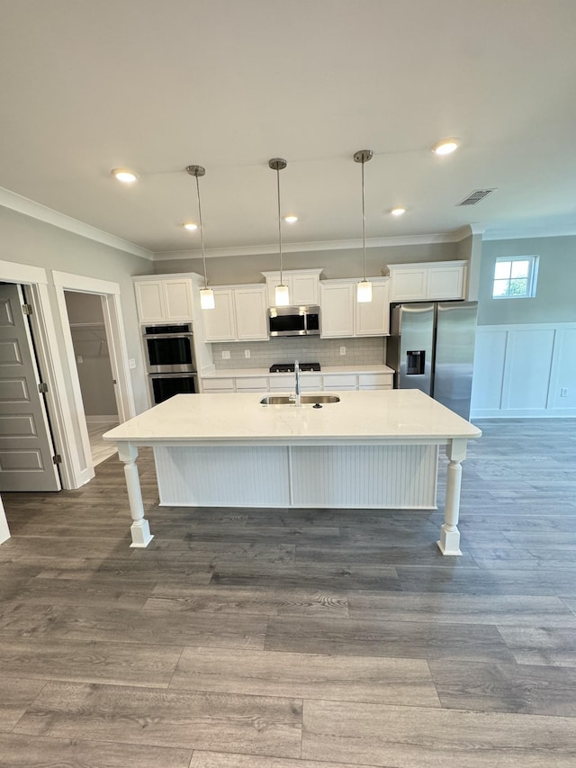 kitchen with appliances with stainless steel finishes, pendant lighting, white cabinetry, sink, and crown molding