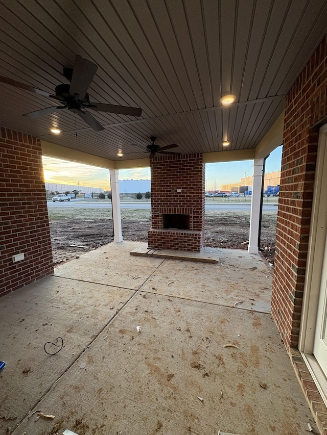 patio terrace at dusk with an outdoor brick fireplace and a water view