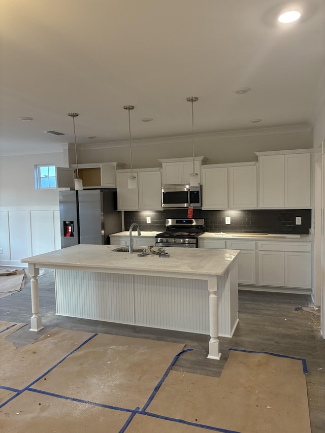 kitchen featuring stainless steel appliances, an island with sink, pendant lighting, and white cabinets