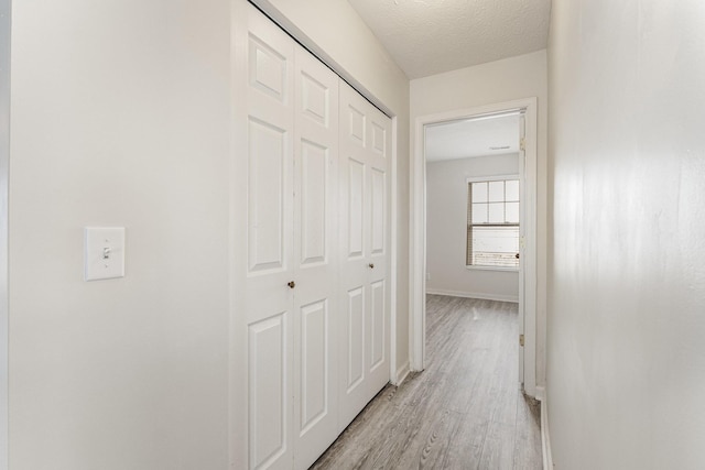 hallway featuring a textured ceiling and light wood-type flooring