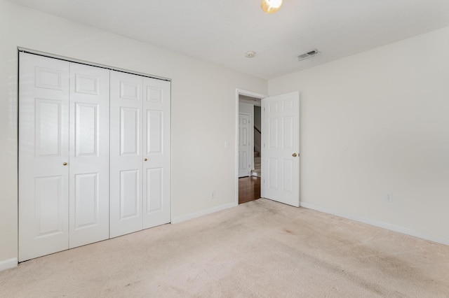 unfurnished bedroom featuring light colored carpet and a closet