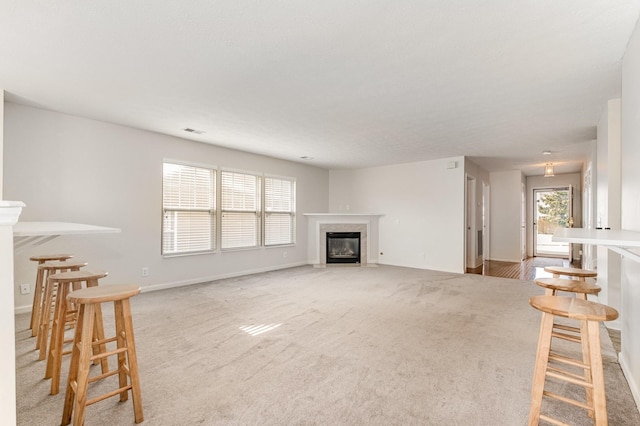 unfurnished living room with a wealth of natural light, light colored carpet, and a fireplace