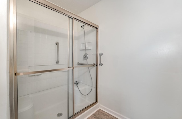 bathroom with hardwood / wood-style flooring and a shower with door