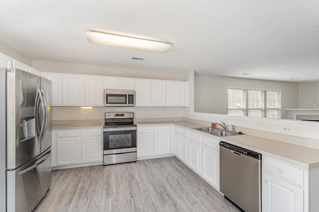 kitchen featuring sink, white cabinetry, light hardwood / wood-style flooring, appliances with stainless steel finishes, and kitchen peninsula