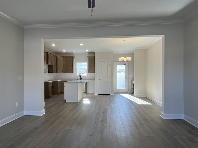 kitchen with sink, crown molding, hardwood / wood-style flooring, a kitchen island, and pendant lighting