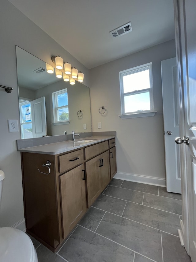 bathroom featuring vanity, a wealth of natural light, and toilet