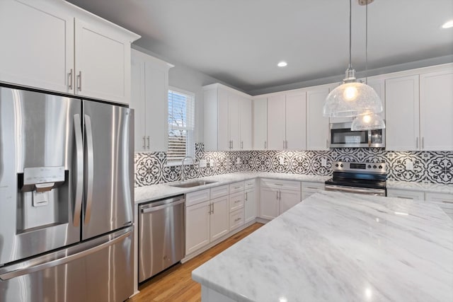 kitchen featuring sink, white cabinets, backsplash, hanging light fixtures, and stainless steel appliances