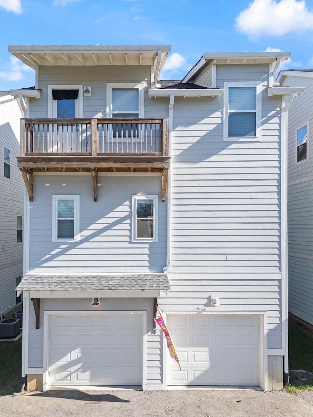 view of front facade with a garage, a balcony, and central air condition unit