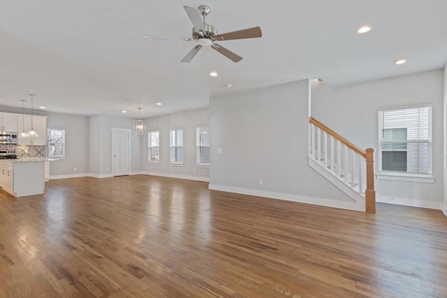 unfurnished living room with hardwood / wood-style floors and ceiling fan with notable chandelier