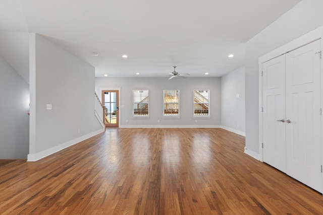 unfurnished living room with wood-type flooring, a healthy amount of sunlight, and ceiling fan