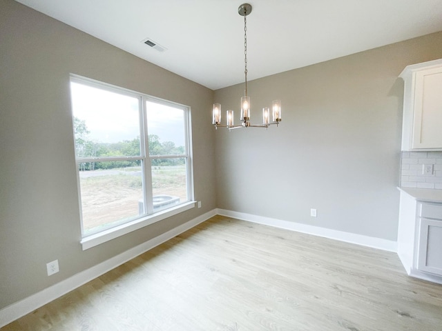 unfurnished dining area with light hardwood / wood-style flooring and a notable chandelier