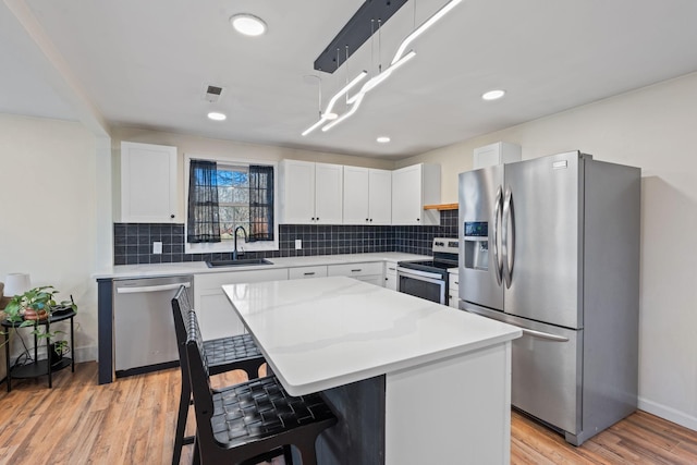 kitchen with sink, white cabinetry, a kitchen breakfast bar, a kitchen island, and stainless steel appliances