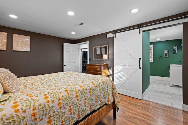 bedroom with hardwood / wood-style flooring and a barn door