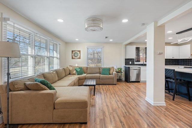 living room with sink, light hardwood / wood-style flooring, and a healthy amount of sunlight