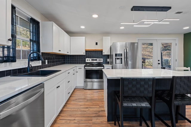 kitchen with white cabinetry, appliances with stainless steel finishes, sink, and a kitchen bar