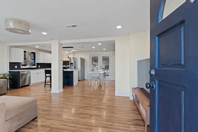 living room featuring sink, french doors, and light wood-type flooring