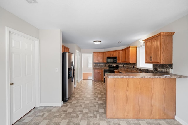 kitchen with decorative backsplash, a sink, a peninsula, and black appliances