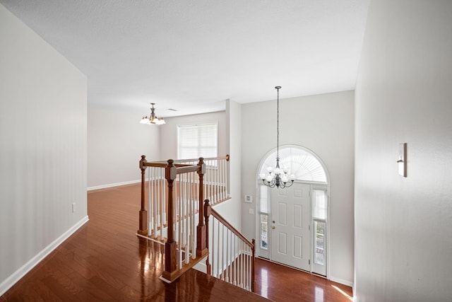 entryway with a chandelier, wood-type flooring, and baseboards