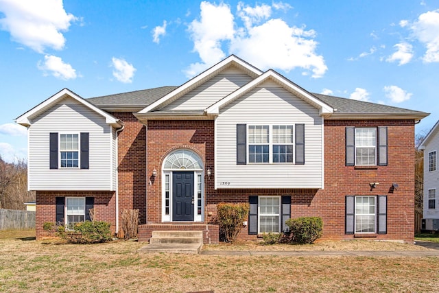 bi-level home featuring brick siding and a front lawn