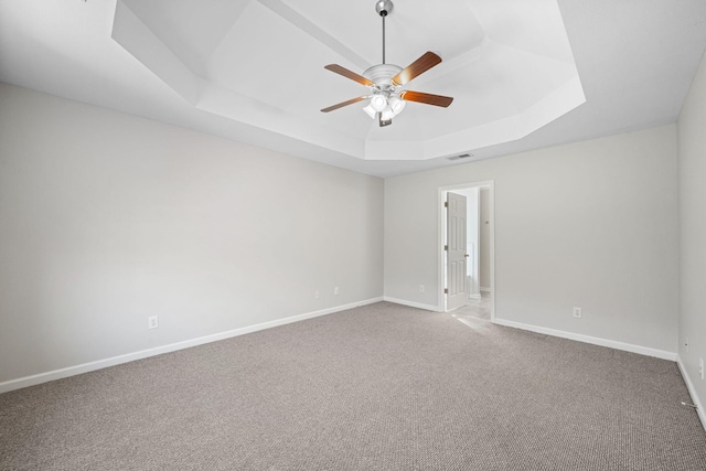 carpeted spare room with ceiling fan, baseboards, visible vents, and a raised ceiling