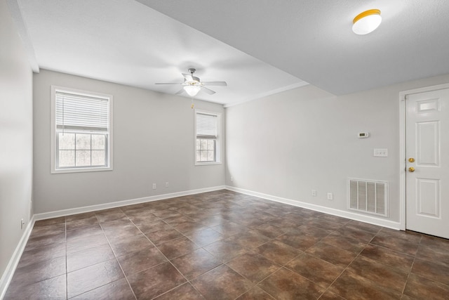 spare room featuring baseboards, visible vents, ceiling fan, and dark tile patterned flooring