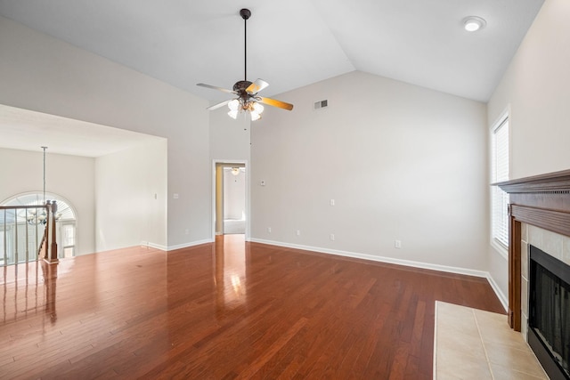 unfurnished living room featuring lofted ceiling, a fireplace, wood finished floors, visible vents, and baseboards