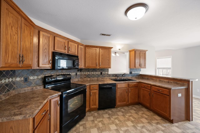 kitchen featuring black appliances, a peninsula, a sink, and brown cabinets