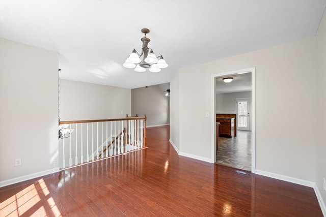 unfurnished room with wood-type flooring, baseboards, and ceiling fan with notable chandelier