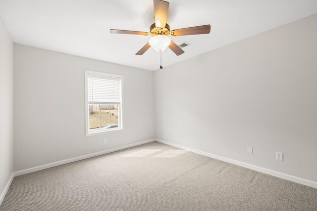 carpeted spare room with visible vents, ceiling fan, and baseboards