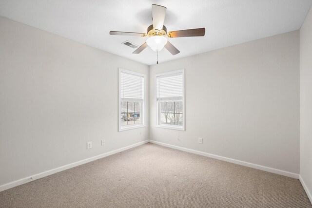 spare room with carpet, visible vents, baseboards, and ceiling fan