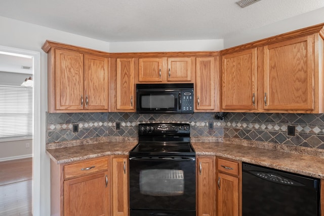 kitchen featuring black appliances, brown cabinets, wood finished floors, and decorative backsplash