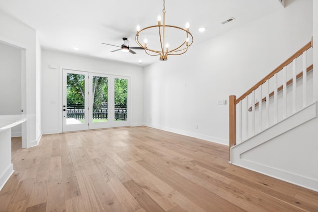 unfurnished living room featuring ceiling fan with notable chandelier and light hardwood / wood-style flooring