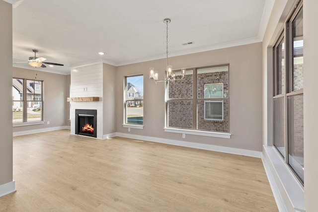 unfurnished living room featuring ornamental molding, ceiling fan with notable chandelier, a fireplace, and light hardwood / wood-style floors