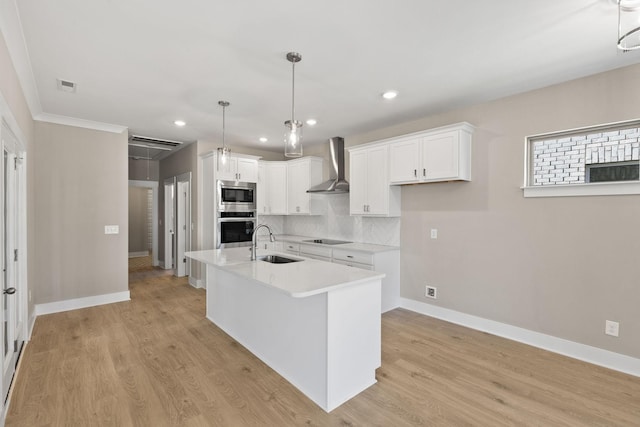 kitchen featuring sink, appliances with stainless steel finishes, pendant lighting, wall chimney range hood, and white cabinets