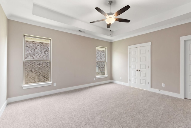 unfurnished bedroom with ceiling fan, carpet flooring, a tray ceiling, and crown molding