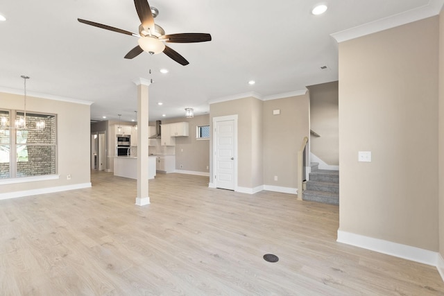 unfurnished living room featuring crown molding, ceiling fan with notable chandelier, and light hardwood / wood-style flooring