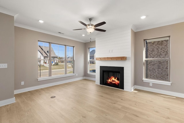 unfurnished living room with ornamental molding, light hardwood / wood-style floors, a large fireplace, and ceiling fan