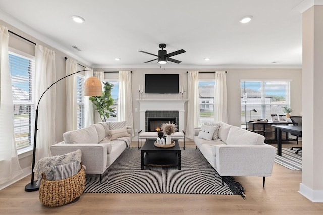 living room featuring ceiling fan, plenty of natural light, a fireplace, and light hardwood / wood-style flooring