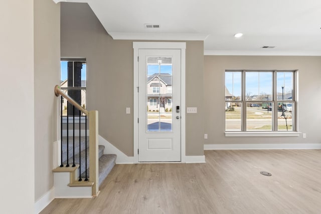 entryway with light hardwood / wood-style flooring, ornamental molding, and a healthy amount of sunlight