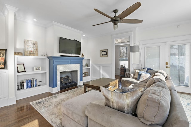 living room with a tile fireplace, crown molding, dark hardwood / wood-style flooring, and french doors