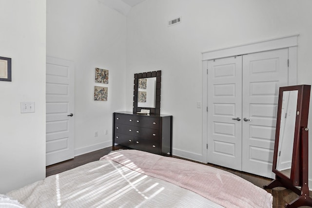 bedroom featuring dark wood-type flooring, a closet, and a high ceiling