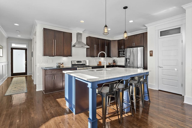 kitchen with sink, dark brown cabinets, stainless steel appliances, an island with sink, and wall chimney exhaust hood