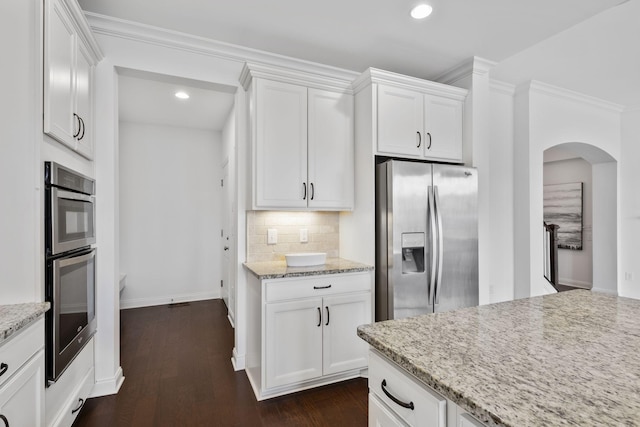 kitchen with light stone countertops, decorative backsplash, stainless steel appliances, and white cabinets