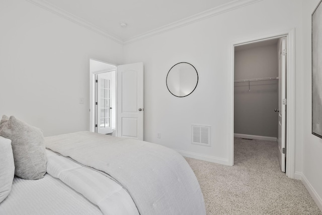 carpeted bedroom featuring crown molding, a spacious closet, and a closet