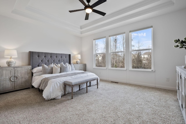 carpeted bedroom featuring ceiling fan and a tray ceiling