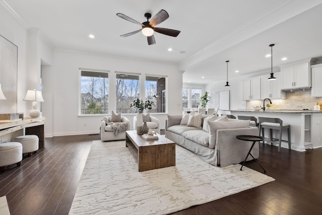 living room featuring ceiling fan, ornamental molding, dark hardwood / wood-style floors, and sink