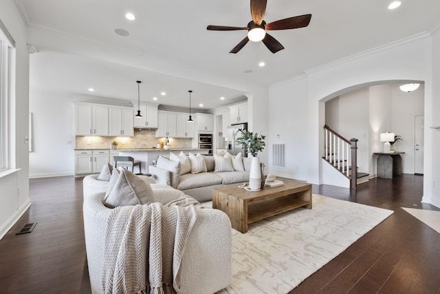 living room with crown molding, dark wood-type flooring, and ceiling fan