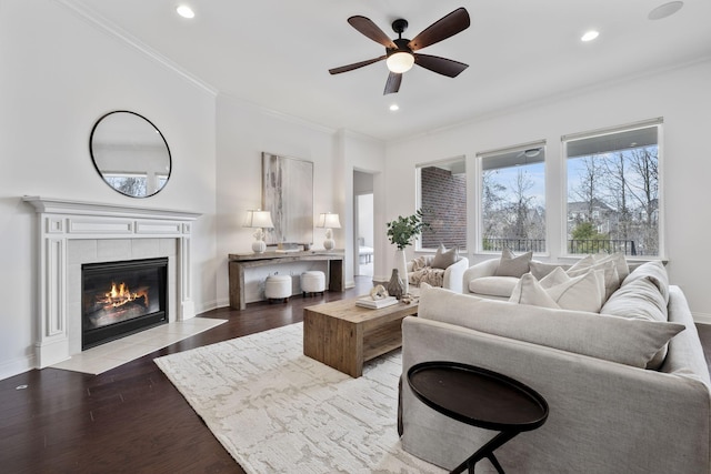 living room featuring crown molding, ceiling fan, light hardwood / wood-style floors, and a tile fireplace